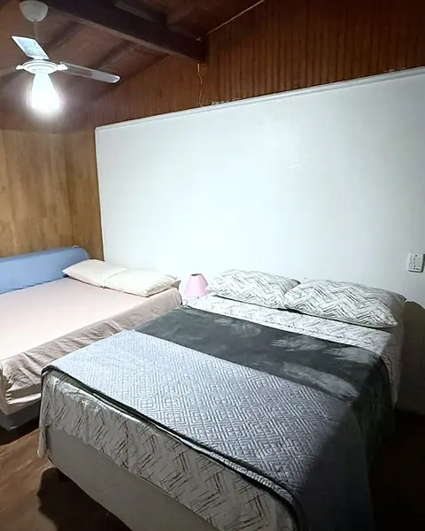 Quarto com duas camas, parede de madeira e ventilador de teto